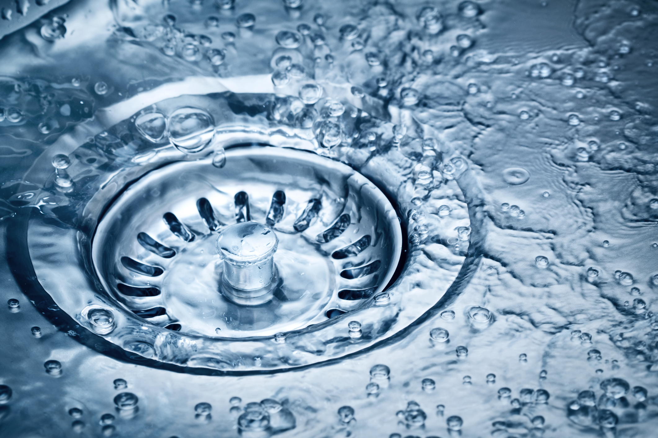 Water being poured into the drain of a kitchen sink.